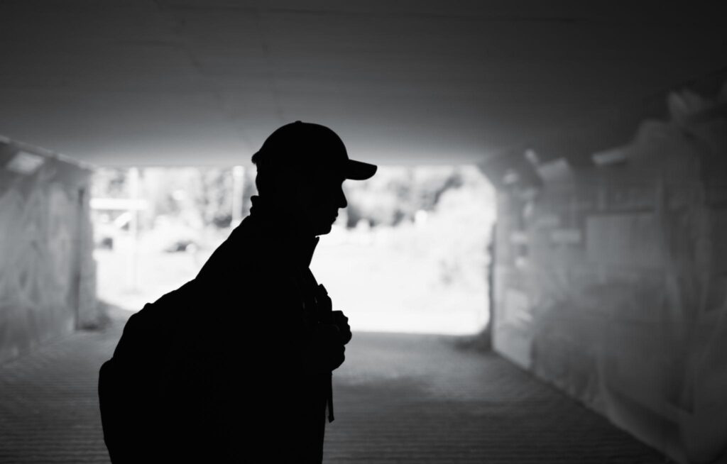 man silhouette standing outside apartment building at night feeling hopeless after rental rejection with a criminal record